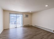 Thumbnail 23 of 43 - the living room of an empty apartment with wood flooring and a balcony. Fargo, ND Stonebridge Apartments