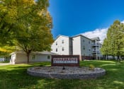 Thumbnail 42 of 43 - An exterior of an apartment with a sign and underground garage out front.  Fargo, ND Stonebridge Apartments.