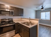 Thumbnail 15 of 20 - an empty kitchen with a sink and stove and a window. Fargo, ND Sunwood Apartments