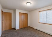 Thumbnail 25 of 28 - an empty living room with carpet and a door to a bedroom. Fargo, ND Thunder Creek Apartments