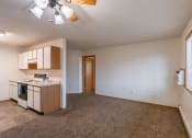 Thumbnail 19 of 28 - an empty living room with a kitchen with a stove and a sink. Fargo, ND Thunder Creek Apartments