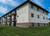 Thumbnail 16 of 16 - The exterior of a three level apartment building with a grass area out front
