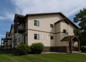 Thumbnail 1 of 2 - Fargo, ND Village Park Apartments. An exterior view of a large apartment building with a grassy area in front of it