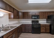 Thumbnail 18 of 26 - a kitchen with black appliances and white countertops. Fargo, ND Village West Apartments