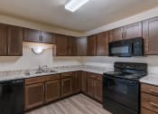 Thumbnail 17 of 26 - a kitchen with black appliances and white countertops. Fargo, ND Village West Apartments