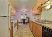 Thumbnail 3 of 26 - a kitchen with wooden cabinets and a dining room in the background. Fargo, ND Village West Apartments