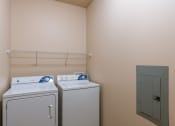 Thumbnail 16 of 61 - a laundry room with two washes and a dryer next to a green door. Fargo, ND West Lake Apartments