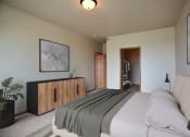 Thumbnail 5 of 61 - a bedroom with a bed and a dresser and a door to a bathroom. West Fargo, ND West Lake Apartments.