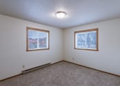 Thumbnail 9 of 9 - the living room of an empty house with two windows. Fargo, ND West Oak Apartments.