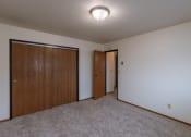 Thumbnail 8 of 9 - a room with a carpeted floor and a door to a closet. Fargo, ND West Oak Apartments.