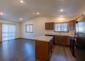 Thumbnail 22 of 42 - a kitchen with black appliances and a living room with two windows. Fargo, ND Westwood Apartments