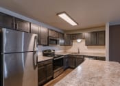 Thumbnail 14 of 24 - a kitchen with stainless steel appliances and dark wood cabinets. Fargo, ND Willow Park Apartments