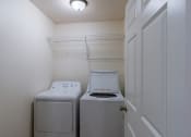 Thumbnail 16 of 24 - a laundry room with a shelf, washer, and dryer. Fargo, ND Willow Park Apartments