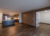 Thumbnail 13 of 24 - a living room with a brown wall and a kitchen in the background. Fargo, ND Willow Park Apartments