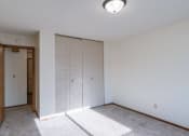 Thumbnail 8 of 15 - a bedroom with white walls and a door to a closet. Fargo, ND Windsor Apartments