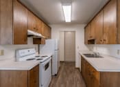 Thumbnail 5 of 15 - an empty kitchen with white appliances and wooden cabinets. Fargo, ND Windsor Apartments