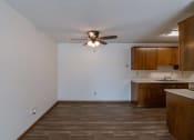 Thumbnail 14 of 15 - an empty living room with a ceiling fan and a kitchen. Fargo, ND Windsor Apartments