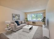 Thumbnail 1 of 17 - a living room with a couch coffee table and a window. Fargo, ND Woodland Apartments