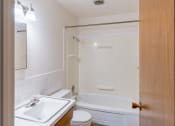 Thumbnail 14 of 17 - a bathroom with a sink toilet and tub and a mirror. Fargo, ND Woodland Apartments |