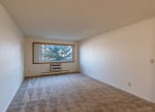 Thumbnail 5 of 17 - an empty living room with a window in the corner. Fargo, ND Woodland Apartments