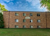 Thumbnail 16 of 17 - a brick building with a sign on the side of it. Fargo, ND Woodland Apartments