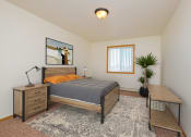 Thumbnail 8 of 11 - a bedroom with a bed and a desk and a window. Moorhead, MN Woodstone Apartments