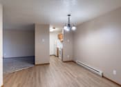 Thumbnail 18 of 26 - the living room and kitchen of an empty apartment with wood flooring. Fargo, ND Briar Pointe Apartments