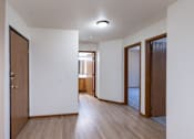 Thumbnail 23 of 26 - an empty living room and hallway with wood floors and white walls. Fargo, ND Briar Pointe Apartments