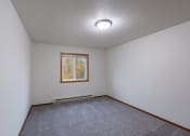 Thumbnail 17 of 33 - the living room of an empty house with carpet and a window. Fargo, ND Brownstone Apartments