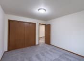Thumbnail 18 of 33 - a living room with carpet and a door to a bedroom. Fargo, ND Brownstone Apartments