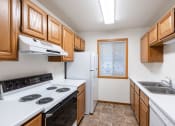 Thumbnail 13 of 33 - a kitchen with white appliances and wooden cabinets. Fargo, ND Brownstone Apartments