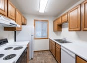 Thumbnail 14 of 33 - a kitchen with white appliances and wooden cabinets. Fargo, ND Brownstone Apartments