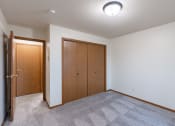 Thumbnail 29 of 33 - an empty living room with carpet and a door to a closet. Fargo, ND Brownstone Apartments