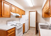Thumbnail 26 of 33 - a kitchen with white appliances and wooden cabinets and a white refrigerator. Fargo, ND Brownstone Apartments