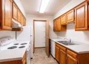 Thumbnail 27 of 33 - a kitchen with wood cabinets and white appliances and a sink. Fargo, ND Brownstone Apartments