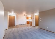 Thumbnail 25 of 33 - an empty living room with a kitchen in the background. Fargo, ND Brownstone Apartments