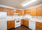 Thumbnail 35 of 41 - an empty kitchen with white appliances and wooden cabinets. Fargo, ND Carlton Place Apartments