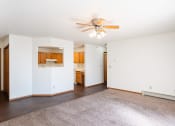 Thumbnail 33 of 41 - a living room with a ceiling fan and kitchen in the background. Fargo, ND Carlton Place Apartments