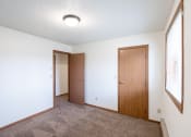Thumbnail 9 of 15 - an empty living room with a door to a closet and a window. Fargo, ND Cedar Pointe Apartments