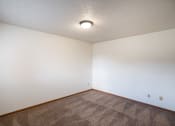 Thumbnail 10 of 15 - an empty living room with carpet and white walls. Fargo, ND Cedar Pointe Apartments