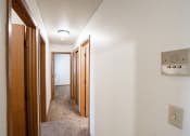 Thumbnail 13 of 15 - a hallway with wood doors and a light on the ceiling. Fargo, ND Cedar Pointe Apartments