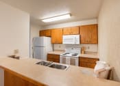 Thumbnail 7 of 15 - a kitchen with white appliances and wooden cabinets and a sink. Fargo, ND Cedar Pointe Apartments