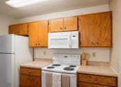 Thumbnail 6 of 15 - a kitchen with white appliances and wooden cabinets and a refrigerator. Fargo, ND Cedar Pointe Apartments