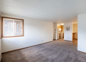 Thumbnail 5 of 15 - an empty living room with a large window and a carpeted floor. Fargo, ND Cedar Pointe Apartments