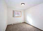 Thumbnail 16 of 42 - an empty room with carpet and a window. Fargo, ND Country Club Apartments