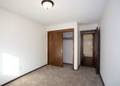 Thumbnail 17 of 42 - a room with a carpeted floor and a door to a closet and a hallway. Fargo, ND Country Club Apartments