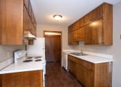 Thumbnail 11 of 42 - a kitchen with white counters and wooden cabinets and a stove and sink. Fargo, ND Country Club Apartments