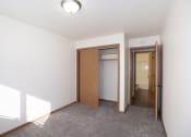 Thumbnail 38 of 42 - an empty living room with a door to a closet and a hallway to a bathroom. Fargo, ND Country Club Apartments