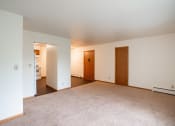 Thumbnail 6 of 18 - a living room with carpet and white walls and two doors. Fargo, ND Crown Court 1 Apartments