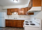 Thumbnail 14 of 18 - an empty kitchen with white appliances and wooden cabinets. Fargo, ND Crown Court 1 Apartments